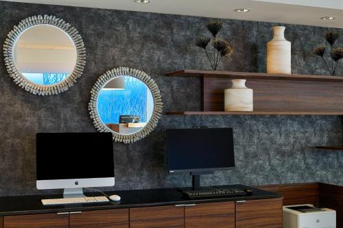 a desk with a computer and two mirrors on a wall at Fairfield Inn & Suites by Marriott Columbus Airport in Columbus
