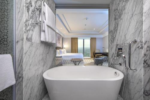 a bathroom with a bath tub and a bedroom at ITC Royal Bengal, a Luxury Collection Hotel, Kolkata in Kolkata