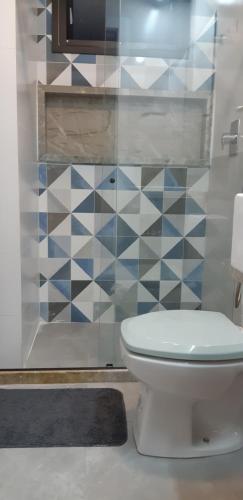 a bathroom with a toilet and a mosaic wall at Ap 305 Praia Castelhanos in Anchieta