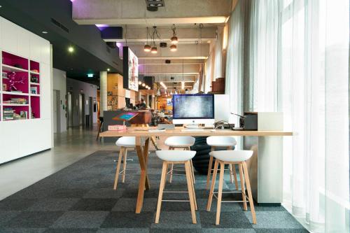 an office with a desk and stools in a room at Moxy Berlin Ostbahnhof in Berlin
