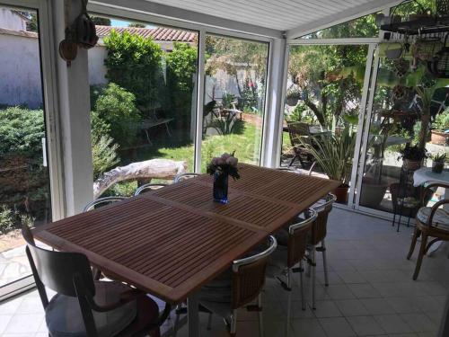 a wooden table and chairs on a screened porch at Entre mer et forêt, idéalement située in Rivedoux-Plage