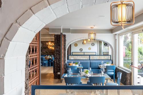 a dining room with blue tables and chairs and an archway at Delta Hotels by Marriott Giardini Naxos in Giardini Naxos
