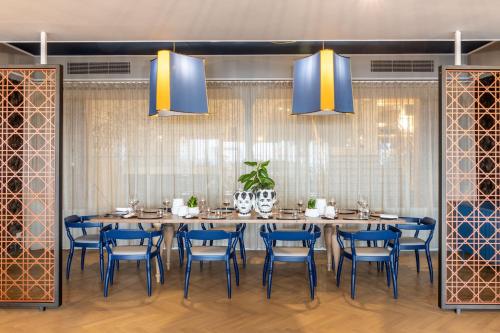 a dining room with a long table and blue chairs at Delta Hotels by Marriott Giardini Naxos in Giardini Naxos