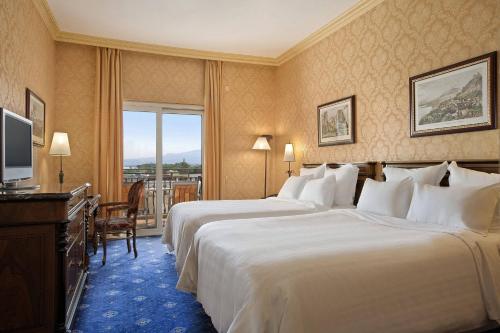 a hotel room with two beds and a television at Delta Hotels by Marriott Giardini Naxos in Giardini Naxos