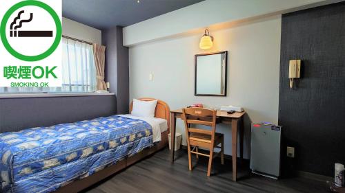 大阪市にあるアズガ－デン日本橋のベッド、テーブル、デスクが備わる小さな客室です。