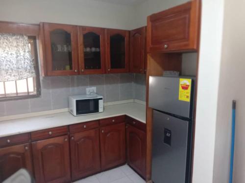 a kitchen with wooden cabinets and a refrigerator at Spintex Villas - Available for Long Term Rentals in Ablekuma