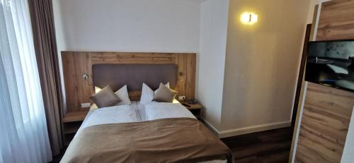 a bedroom with a bed with white sheets and pillows at Heidehotel Soltauer Hof in Soltau