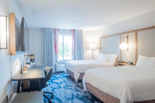 a hotel room with two beds and a desk at Fairfield Inn & Suites Denton in Denton