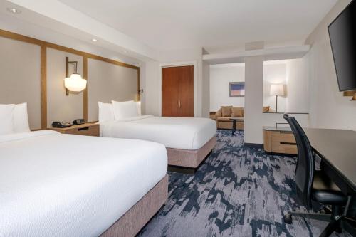 a hotel room with two beds and a desk at Fairfield Inn & Suites Denton in Denton