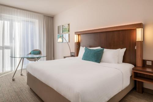 a hotel room with a large bed and a table at Courtyard by Marriott Cologne in Cologne