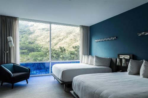 Habitación de hotel con 2 camas y ventana grande. en Marriott Maracay Golf Resort, en Maracay