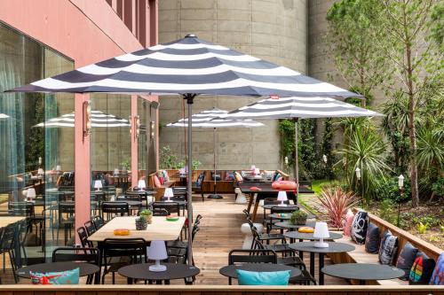 a patio with tables and chairs under an umbrella at Moxy Bordeaux in Bordeaux