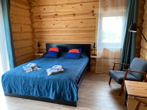 Un dormitorio con una cama azul con almohadas azules y rojas en Zvejnieku māja en Jūrkalne