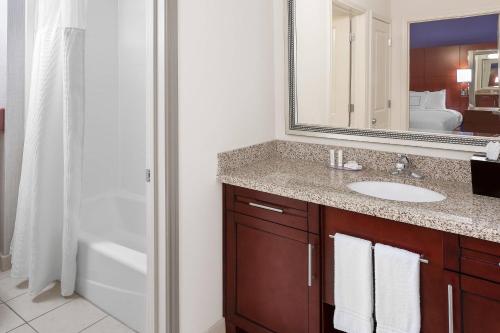 a bathroom with a sink and a mirror and a tub at Residence Inn by Marriott Houston Katy Mills in Katy