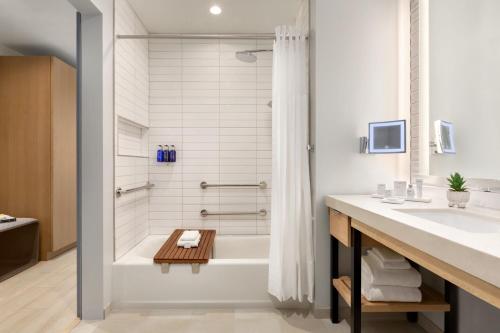 a bathroom with a bath tub and a sink at The Viv Hotel, Anaheim, a Tribute Portfolio Hotel in Anaheim