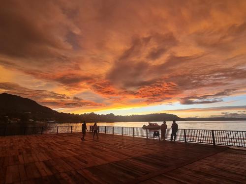 a group of people standing on a pier at sunset at PURNAMA BALIGE HOTEL in Balige