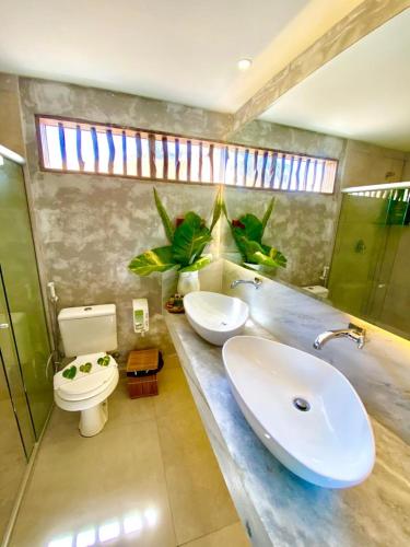 a bathroom with two sinks and a toilet and a window at Villa Pantai Milagres Exclusive Hotel in São Miguel dos Milagres
