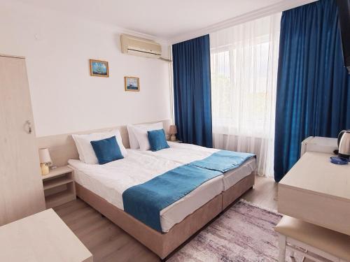 1 dormitorio con 1 cama grande y cortinas azules en Guest House Kolev, en Nesebar