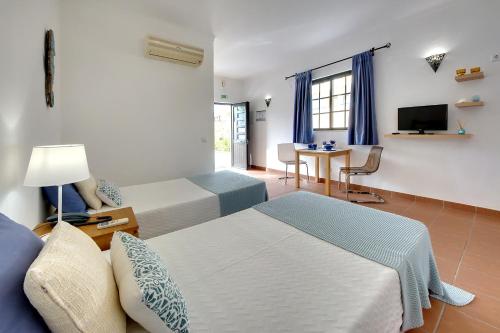 a hotel room with two beds and a table at Apartamentos Turisticos Novochoro in Albufeira