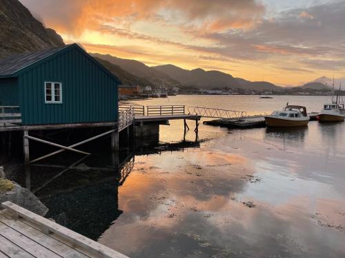 un molo con barche e un edificio sull'acqua di Kræmmervika Rorbuer - Rustic Cabins in Lofoten a Ballstad