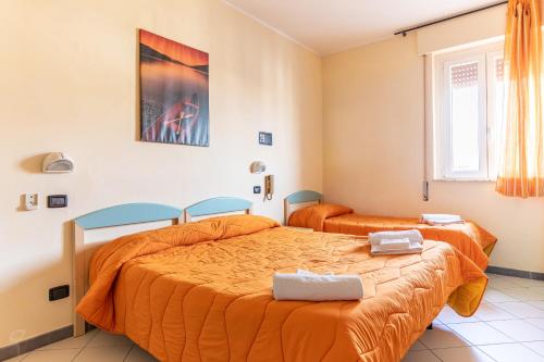 two beds in a room with orange sheets at Hotel Paolina in Viareggio