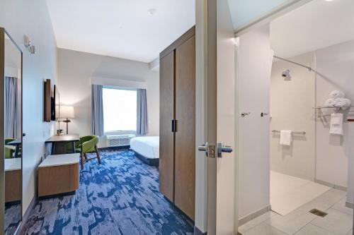 a hotel room with a bathroom with a bed and a shower at Fairfield Inn & Suites by Marriott Houston NASA/Webster in Webster