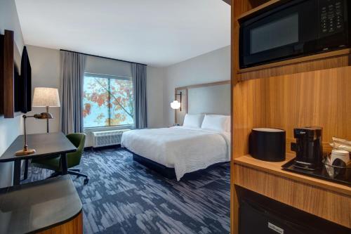 a hotel room with a bed and a flat screen tv at Fairfield by Marriott Inn & Suites Rochester Hills in Rochester Hills