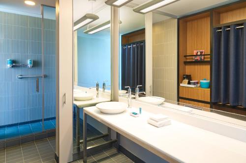 a bathroom with two sinks and two mirrors at Aloft Hotel Plano in Plano