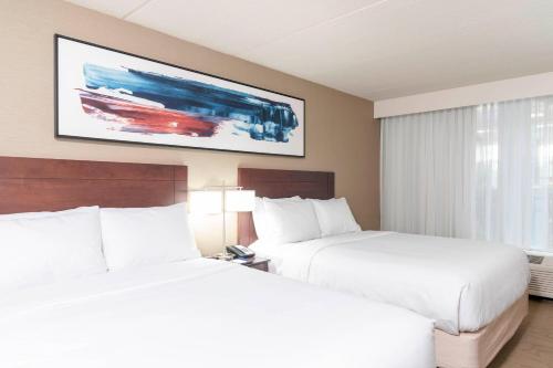 two beds in a hotel room with a tv on the wall at Delta Hotels by Marriott Kalamazoo Conference Center in Kalamazoo