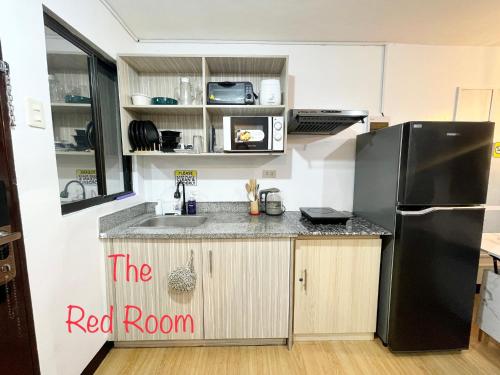 a kitchen with a black refrigerator and a sink at The Red Room 2bed room Condo in Imus