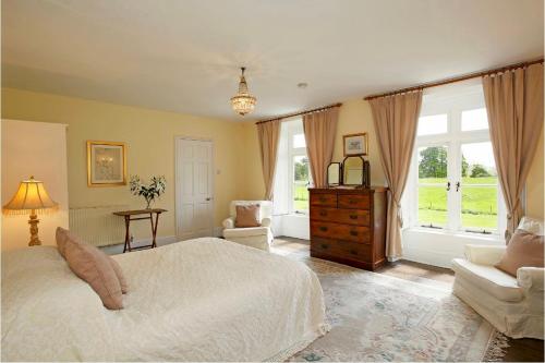 a bedroom with a bed and a chair and windows at Newcourt Manor in Hereford