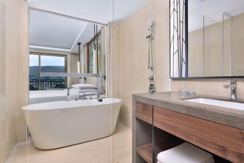 baño con bañera blanca grande y lavamanos en Courtyard by Marriott Mahabaleshwar, en Mahabaleshwar