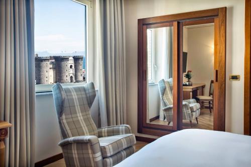 a hotel room with a bed and a chair and a window at Renaissance Naples Hotel Mediterraneo in Naples