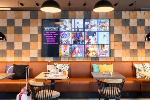 a restaurant with a bench and two tables and a tv at Moxy Wuerzburg in Würzburg
