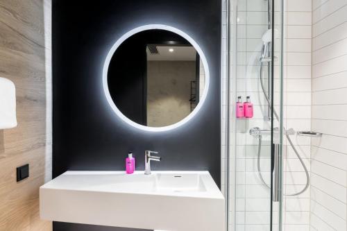 ein Badezimmer mit einem weißen Waschbecken und einem Spiegel in der Unterkunft Moxy Wuerzburg in Würzburg