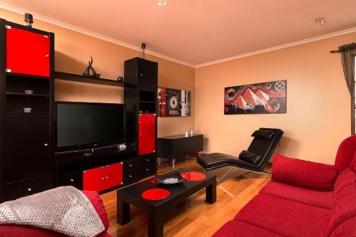 a living room with a red couch and a flat screen tv at KING´S HOUSE (Sea View and Indoor BBQ) in Estreito da Calheta