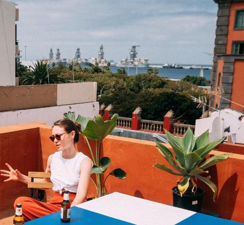 une femme assise à une table sur un balcon dans l'établissement Doña Rose Coliving, à Las Palmas de Gran Canaria