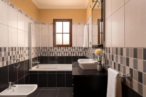 - une salle de bains en noir et blanc avec deux lavabos et une baignoire dans l'établissement KING´S HOUSE (Sea View and Indoor BBQ), à Estreito da Calheta