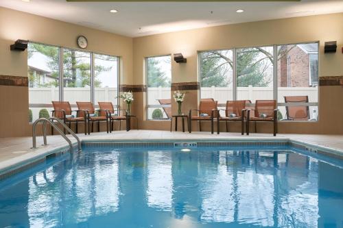 una piscina en una habitación de hotel con sillas alrededor en Courtyard by Marriott Evansville East en Evansville