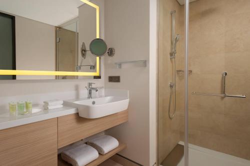 a bathroom with a sink and a shower at Courtyard by Marriott Chisinau in Chişinău