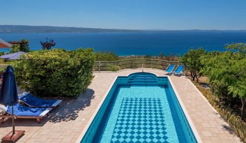 uma piscina com cadeiras e o oceano ao fundo em Villa Aquarius, Podstrana, Croatia em Podstrana