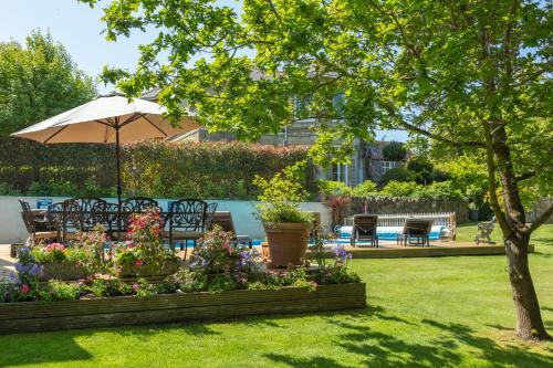 um jardim com cadeiras e um guarda-sol e flores em Luccombe Villa Holiday Apartments em Shanklin