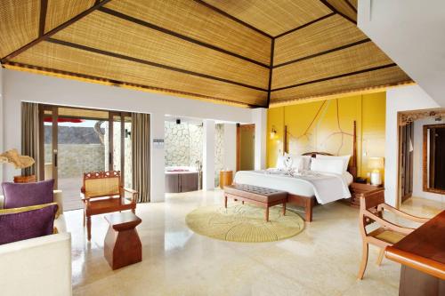 a bedroom with a bed and a table and chairs at Le Meridien Bali Jimbaran in Jimbaran