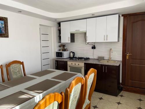 a kitchen with a table and chairs and a kitchen with white cabinets at Rodynnyi Zatyshok in Verkhovyna