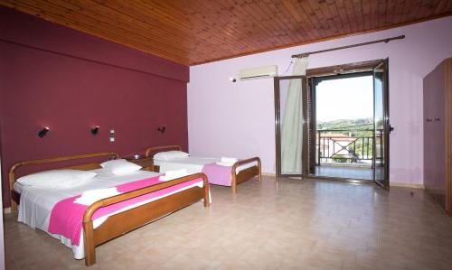 a bedroom with two beds and a large window at Petania Hotel & Apartments in Lixouri