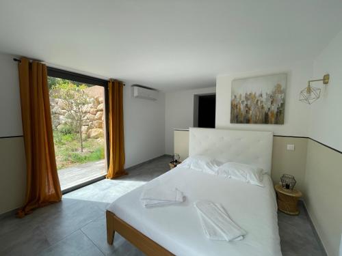 een slaapkamer met een wit bed en een groot raam bij Appartement Zuria T3 in Bonifacio