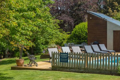 a wooden fence with lounge chairs in a yard at Luccombe Villa Holiday Apartments in Shanklin