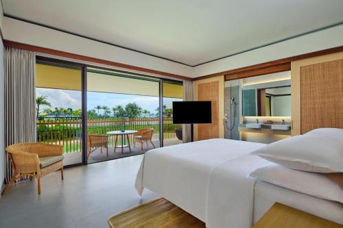 a bedroom with a large bed and a balcony at Sheraton Belitung Resort in Tanjungbinga