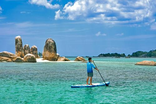 a man standing on a paddle board in the water at Sheraton Belitung Resort in Tanjungbinga