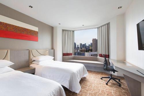 a hotel room with two beds and a desk and a window at Four Points by Sheraton Singapore, Riverview in Singapore